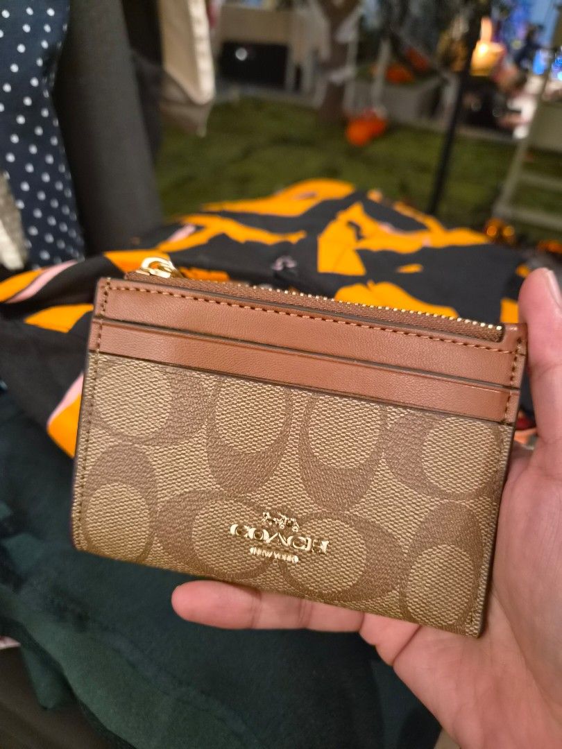 Coach Signature Canvas Mini Zip Case Brown (Category: Luxury Bags & Wallets) located in Paranaque City. Submitted by regf_01 (Listing ID 1465669719, Image 2). Description: - Authentic Coach Card Case - Color: Brown Signature Canvas with Tan Leather Trim - Hardware: Gold-tone - Closure: Zip-top with leather pull - Features: ID window on one side, multiple card slots on the other - Size: Compact, fits easily in pockets and small bags - Condition: L