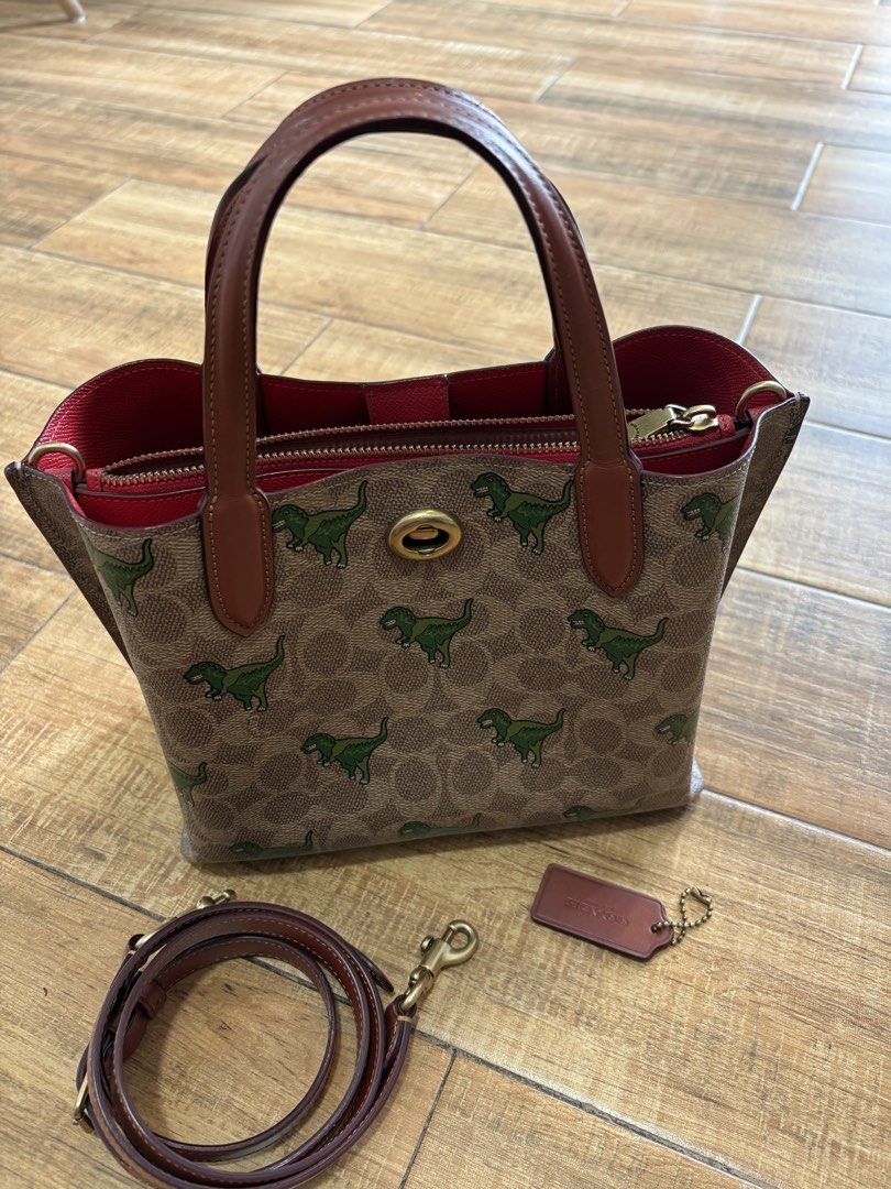 Coach Willow Rexy Dinosaur Print (Authentic) (Category: Luxury Bags & Wallets) located in Makati City. Submitted by kirbybeltran (Listing ID 1465649898, Image 1). Description: - Brand: Coach - Design: Signature canvas with Rexy dinosaur print - Colorway: Brown leather trim and gold-tone hardware - Straps: Dual top handles and a matching detachable shoulder strap - Interior: Red lining with a convenient center zip compartment - Inclusion: Matching