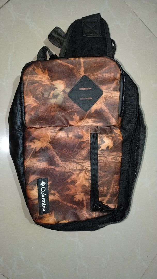 Columbia Camouflage Sling Bag Preloved (Category: Sling Bags) located in Polomolok. Submitted by lastthrift (Listing ID 1465636444, Image 1). Description: - Brand: Columbia - Design: Autumn leaf camo pattern with black accents - Material: Durable polyester - Features: Multiple interior and exterior compartments, sturdy zippers, and adjustable strap - Condition: Tag still attached inside with Japanese text - Perfect for: Everyday use and hands-fre