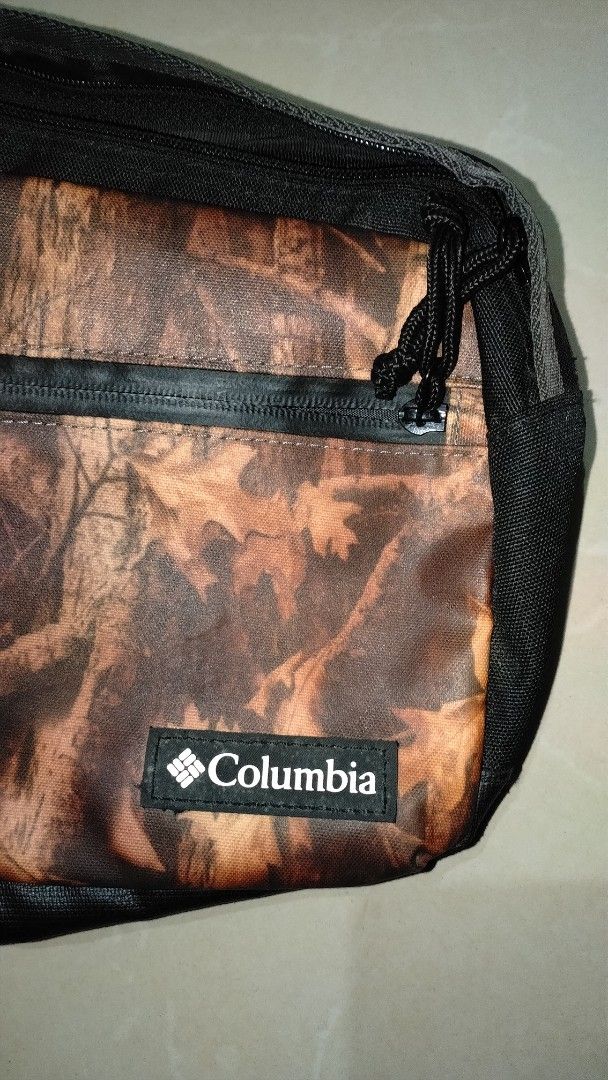 Columbia Camouflage Sling Bag Preloved (Category: Sling Bags) located in Polomolok. Submitted by lastthrift (Listing ID 1465636444, Image 2). Description: - Brand: Columbia - Design: Autumn leaf camo pattern with black accents - Material: Durable polyester - Features: Multiple interior and exterior compartments, sturdy zippers, and adjustable strap - Condition: Tag still attached inside with Japanese text - Perfect for: Everyday use and hands-fre