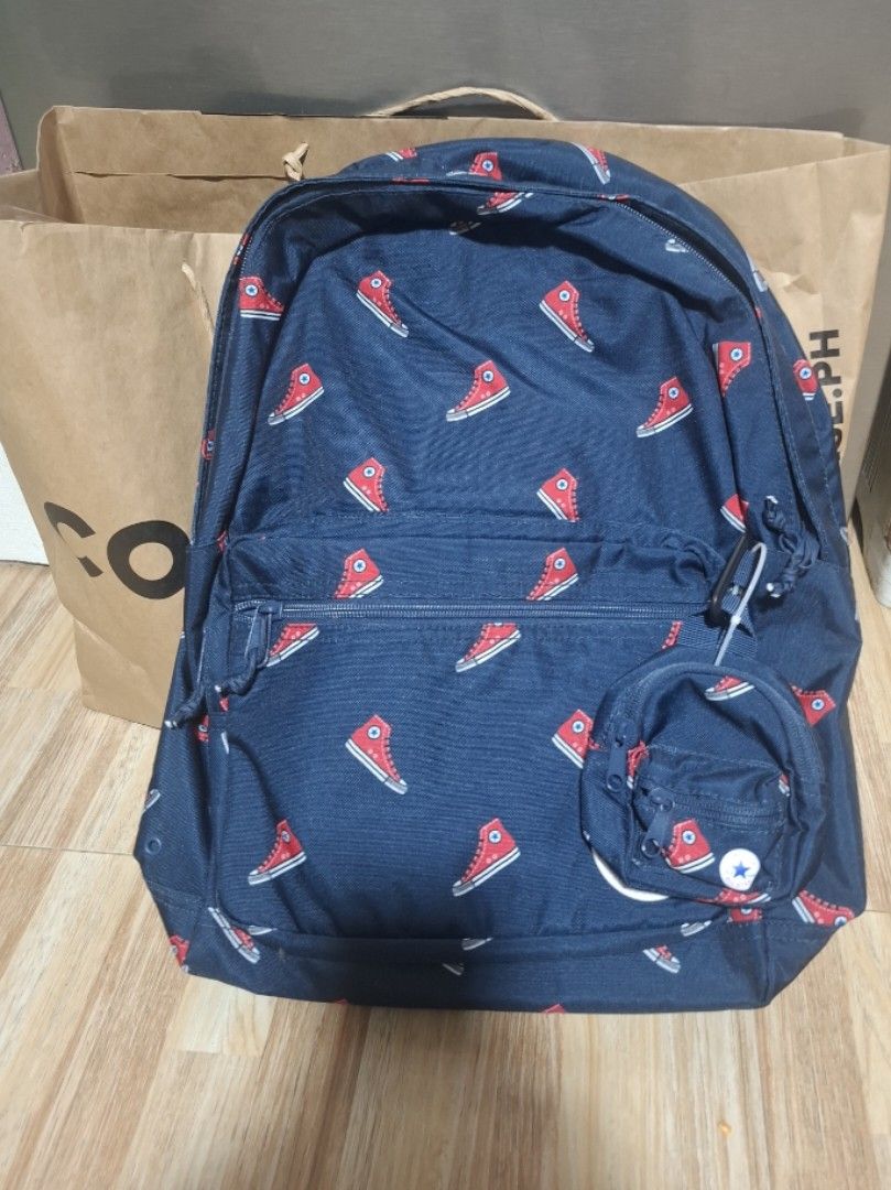 Converse All Star Navy Blue Sneaker Print Backpack (Category: Backpacks) located in Quezon City. Submitted by erekamador (Listing ID 1465701857, Image 1). Description: - Authentic navy blue Converse backpack with all-over red sneaker print - Spacious main zip compartment with a convenient front pocket - Includes a trendy, detachable round pouch near the top - Crafted from sturdy, durable fabric with adjustable straps for comfort - Comes with an o