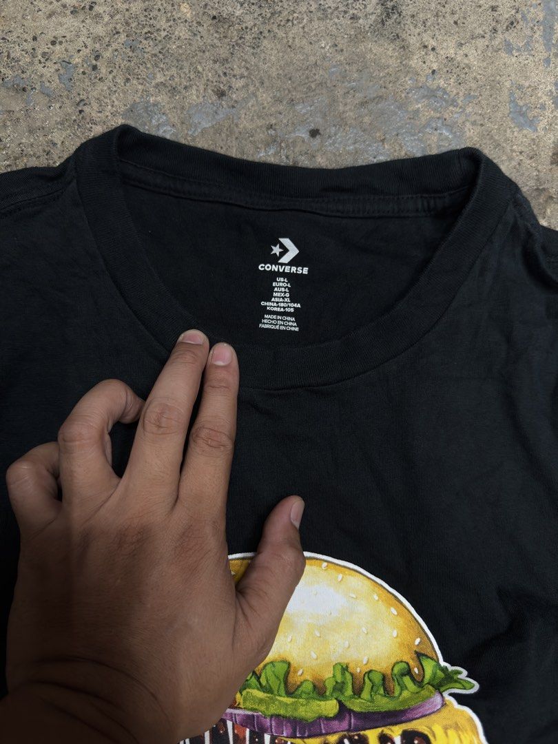 Converse Black Burger Graphic T-Shirt (Category: Tshirts & Polo Shirts ) located in Bustos. Submitted by thenlnclot60500 (Listing ID 1465594776, Image 3). Description: - Brand: Converse - Color: Black with vibrant cheeseburger graphic - Size: US Large / Euro Large / Asia XL - Material: 100% cotton - Condition: Excellent, clean fabric with fully intact neck prints - Details: Small branded tag on the bottom hem.