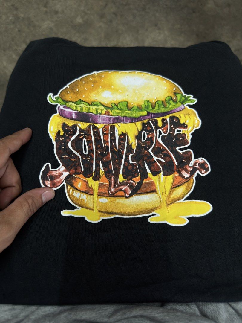 Converse Black Burger Graphic T-Shirt (Category: Tshirts & Polo Shirts ) located in Bustos. Submitted by thenlnclot60500 (Listing ID 1465594776, Image 2). Description: - Brand: Converse - Color: Black with vibrant cheeseburger graphic - Size: US Large / Euro Large / Asia XL - Material: 100% cotton - Condition: Excellent, clean fabric with fully intact neck prints - Details: Small branded tag on the bottom hem.
