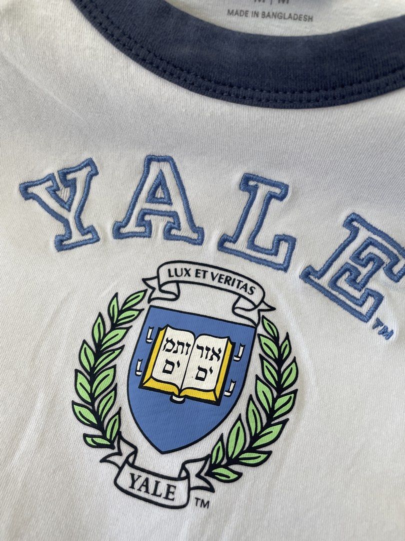 Cotton On Yale University Micro Tee Size M (Category: Shirts) located in Lucena. Submitted by riyizthriftz (Listing ID 1465704184, Image 2). Description: - Brand: Cotton On - Design: Yale University micro tee in white with navy blue raglan sleeves and collar - Detailing: Embroidered Yale crest and lettering across the chest - Fit: Cropped, short sleeve style - Size: M - Material: Soft cotton blend - Condition: Clean, no stains or damage noted.