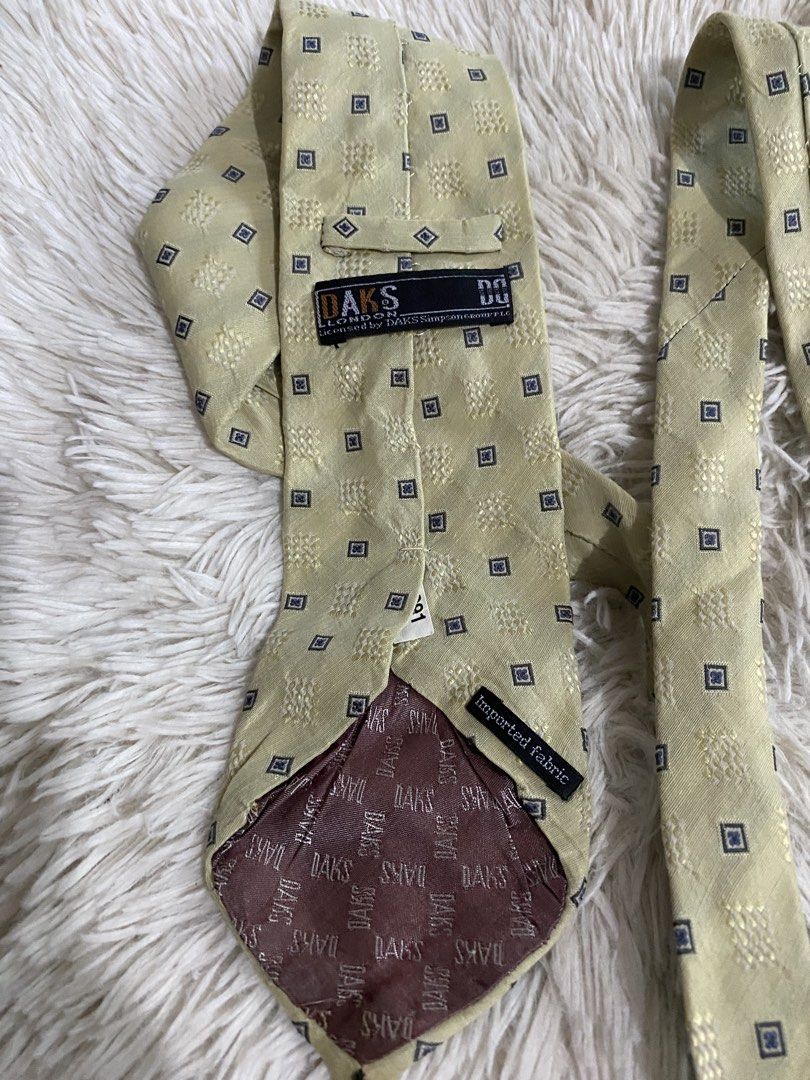 DAKS London Yellow Geometric Pattern Tie (Category: Ties) located in Bulacan. Submitted by rich2545 (Listing ID 1465581602, Image 3). Description: - Brand: DAKS London - Color/Design: Pale yellow with repeating geometric squares - Details: Brown branded lining inside the tip, imported fabric construction - Size: Standard width and length - Best for: Business wear, formal events, and office outfits.