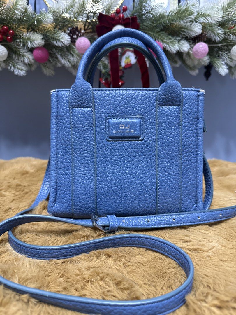 David Jones Blue Tote Handbag (Category: Tote Bags) located in Alaminos. Submitted by jhean1323 (Listing ID 1465584323, Image 1). Description: - Brand: David Jones - Color/Material: Blue pebble textured faux leather - Versatile carry: Dual top handles and a detachable crossbody strap - Secure closure: Zip top - Interior features: Beige fabric lining, one zipper pocket, and metal brand logo plate - Size: Compact, ideal for everyday use - Condition