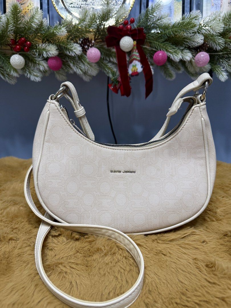 David Jones Cream Crescent Shoulder Bag (Category: Shoulder Bags) located in Alaminos. Submitted by jhean1323 (Listing ID 1465584511, Image 1). Description: - Brand/Model: David Jones crescent shoulder bag - Color/Material: Cream textured fabric with silver-tone hardware and metal front logo - Closure & Interior: Secure zip top closure with a lined interior and a convenient zipped pocket - Strap: Includes an adjustable and removable strap (Flaw n