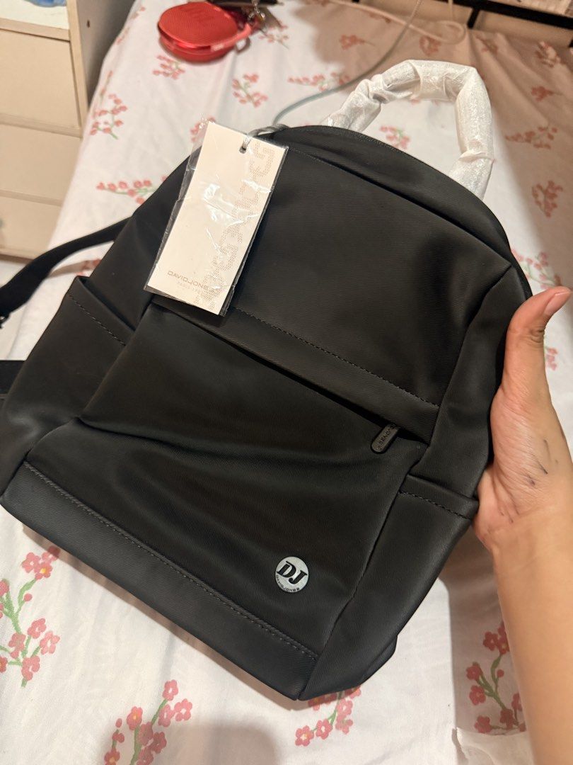 David Jones Paris Black Backpack (Category: Backpacks) located in Quezon City. Submitted by lil_preloooves (Listing ID 1465612971, Image 2). Description: David Jones Paris backpack in black. Compact size with front zipper pocket and side slots. Silver hardware with logo badge. Top carry handle and adjustable straps. Original tag still attached. Protective plastic wrapping still on the handle. RFS: Decluttering. To Small for me. Di nagagamit.