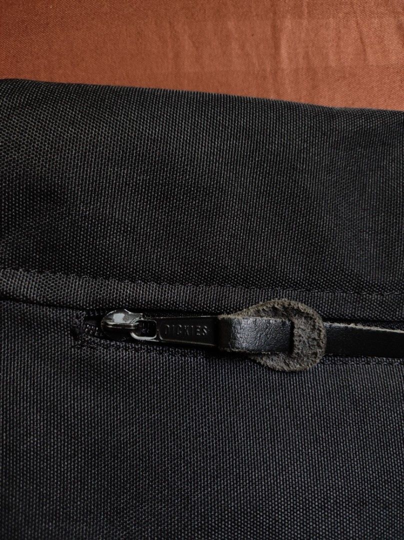 Dickies USA Black Messenger Bag (Category: Sling Bags) located in Batangas. Submitted by astrofinds_ (Listing ID 1465597709, Image 3). Description: - Brand: Dickies - Material: Durable black canvas - Design: Embossed Dickies USA text and classic woven logo patch on the front flap - Closure: Secure zip top under flap with snap button closure - Strap: Adjustable shoulder strap for comfortable wear - Interior: Branded lining with an extra zippered p