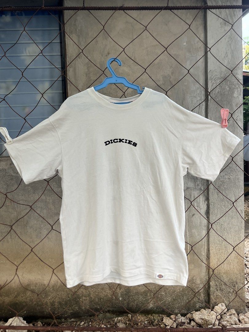 Dickies White Graphic T-Shirt (Category: Tshirts & Polo Shirts ) located in Lapu Lapu. Submitted by vanzfinds_16 (Listing ID 1465663354, Image 1). Description: - Brand: Dickies - Color: Clean off-white - Fit: Regular fit, short sleeves, crew neck - Front Design: Arched black text Dickies logo - Back Design: Large circular mountain landscape graphic with sun and "Dickies Quality Garments Since 1922" text - Details: Small logo tag near bottom hem -