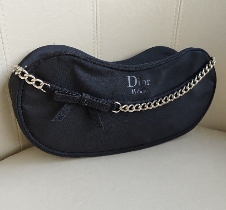 Dior Parfums Black Crescent Shoulder Bag With Chain (Category: Luxury Bags & Wallets) located in Cavite. Submitted by jaimebuala31560 (Listing ID 1465688563, Image 1). Description: - Brand: Dior Parfums - Style: Crescent-shaped shoulder bag - Material: Soft black textile fabric - Details: Silver chain strap across the front with a matching black fabric bow - Size: Compact, ideal for daily essentials or evening outings - Condition: Clean fabric wi