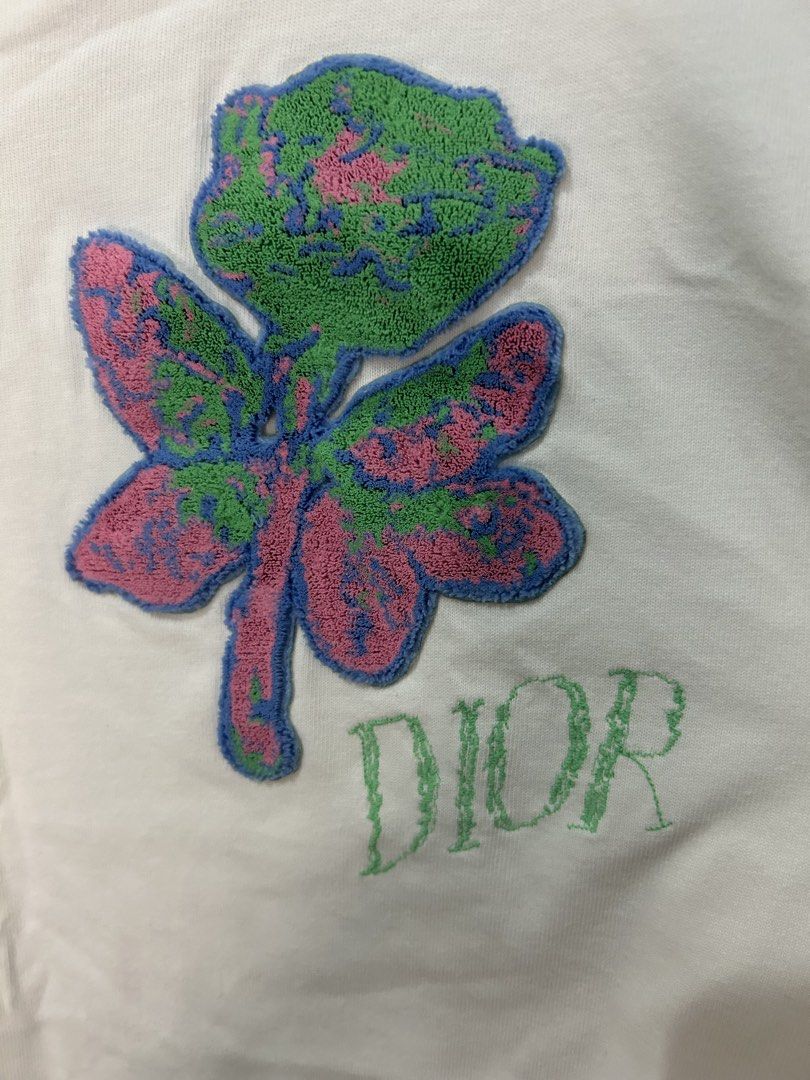 Dior White T-Shirt with Embroidered Rose Patch (Category: Shirts) located in Davao. Submitted by ruggedthrift444 (Listing ID 1465687004, Image 2). Description: - Authentic Dior t-shirt made in Italy - 100% premium cotton for maximum comfort - Features a colorful textured rose patch with green embroidered Dior lettering - Classic crew neck and short sleeves - Standard relaxed fit - Neck tag and interior care labels clearly attached - Condition: Br