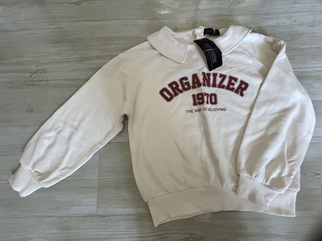 Earth Diver Organizer 1970 Collared Sweatshirt Size 140 (Category: Babies & Kids Fashion) located in Manila. Submitted by ai010 (Listing ID 1465628859, Image 1). Description: - Brand: Earth Diver - Style: White collared sweatshirt with dark red "ORGANIZER 1970 THE WAY OF BELIEVING" chest text - Size: 140 (tag intact) - Details: Rounded collar, back button closure, ribbed cuffs and hem - Material: 55% cotton, 45% polyester (rib includes polyuretha