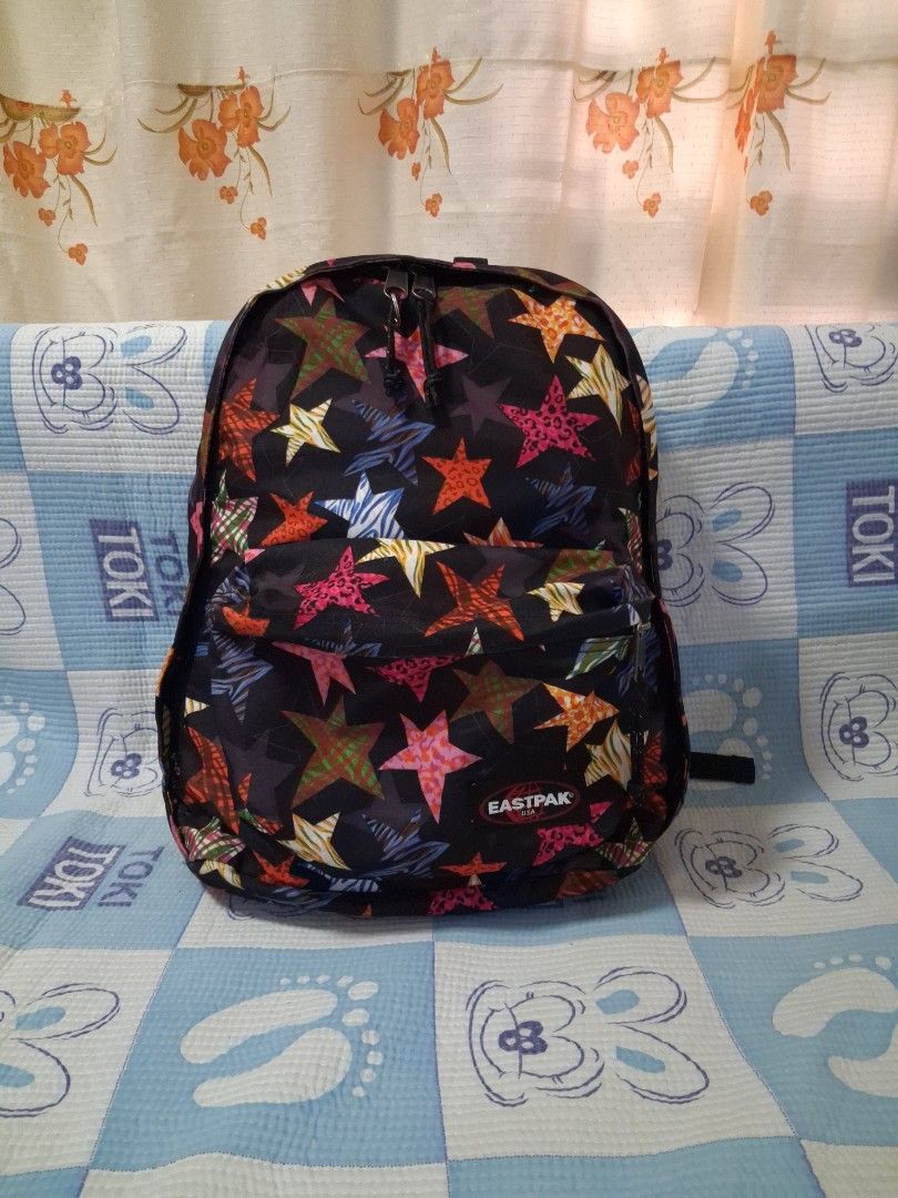 Eastpak Star Pattern Backpack (Category: Backpacks) located in Angeles City. Submitted by anneps (Listing ID 1465697213, Image 1). Description: - Brand: Eastpak - Design: Black base with colorful patterned stars (pink animal print, stripes, and check) - Compartments: 1 roomy main compartment + 1 front zippered pocket - Features: Adjustable shoulder straps and branded dual zipper pull tabs - Material: Durable, clean canvas - Condition: Excellent, 