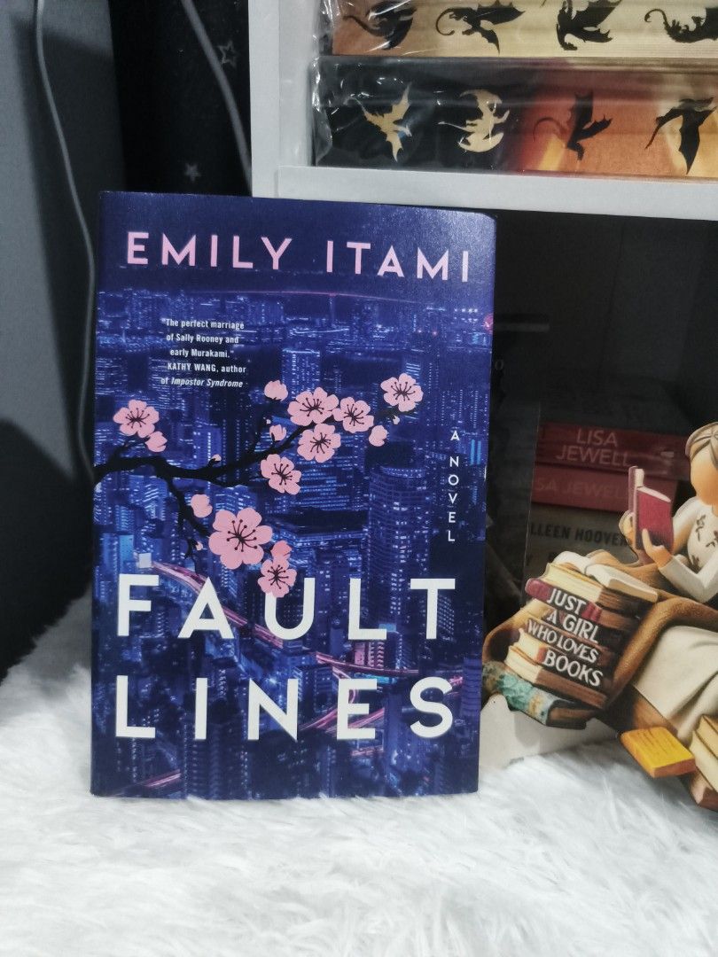Fault Lines by Emily Itami Hardcover Novel (Category: Storybooks) located in Cabuyao City. Submitted by chaptersandwonders143 (Listing ID 1465618966, Image 1). Description: - Title & Author: Fault Lines by Emily Itami - Format: Hardcover edition published by Custom House - Aesthetics: Vibrant blue dust jacket with a striking Tokyo night skyline cover art and lovely pink endpapers - Condition: Clean pages and solid binding, well-maintained - Genre