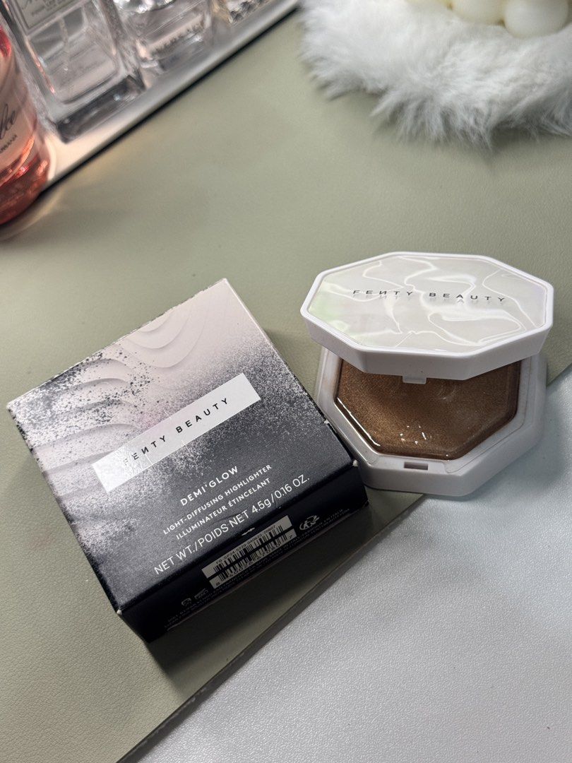 Fenty Beauty Demi'Glow Light-Diffusing Highlighter (Category: Makeup) located in Binan City. Submitted by seoulbeauty_cart (Listing ID 1465586035, Image 1). Description: - Brand: Fenty Beauty - Product: Demi'Glow Light-Diffusing Highlighter - Shade: Bronze shimmer - Size: 4.5g - Condition: Unused (opened for photos only) - Packaging: Includes original box and matching white compact case - Perfect addition to any makeup collection.