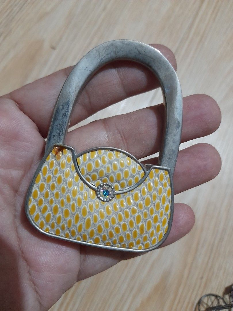 Foldable Bag hook hanger (Category: Luxury Bags & Wallets) located in Bocaue. Submitted by marajapansurplus (Listing ID 1465698857, Image 1). Description: - Foldable handbag hook that transforms into a compact disc - Stylish yellow and white snakeskin print with a blue crystal center and silver-tone hardware - Black non-slip rubber bottom securely grips tables - Keeps your bag clean and safe off restaurant floors - Lightweight and handy accessory