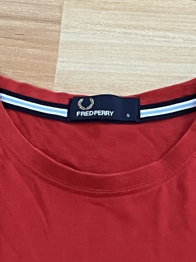 Fred Perry Red T-Shirt Size S (Category: Tshirts & Polo Shirts ) located in Victorias. Submitted by lan1877 (Listing ID 1465675465, Image 3). Description: - Brand: Fred Perry - Style/Model: M6334 - Size: Small - Color: Red with dark blue laurel wreath embroidery - Details: Contrast tipping on inner collar tape, clean cotton fabric, regular fit, straight hem - Condition: Excellent casual wear staple.