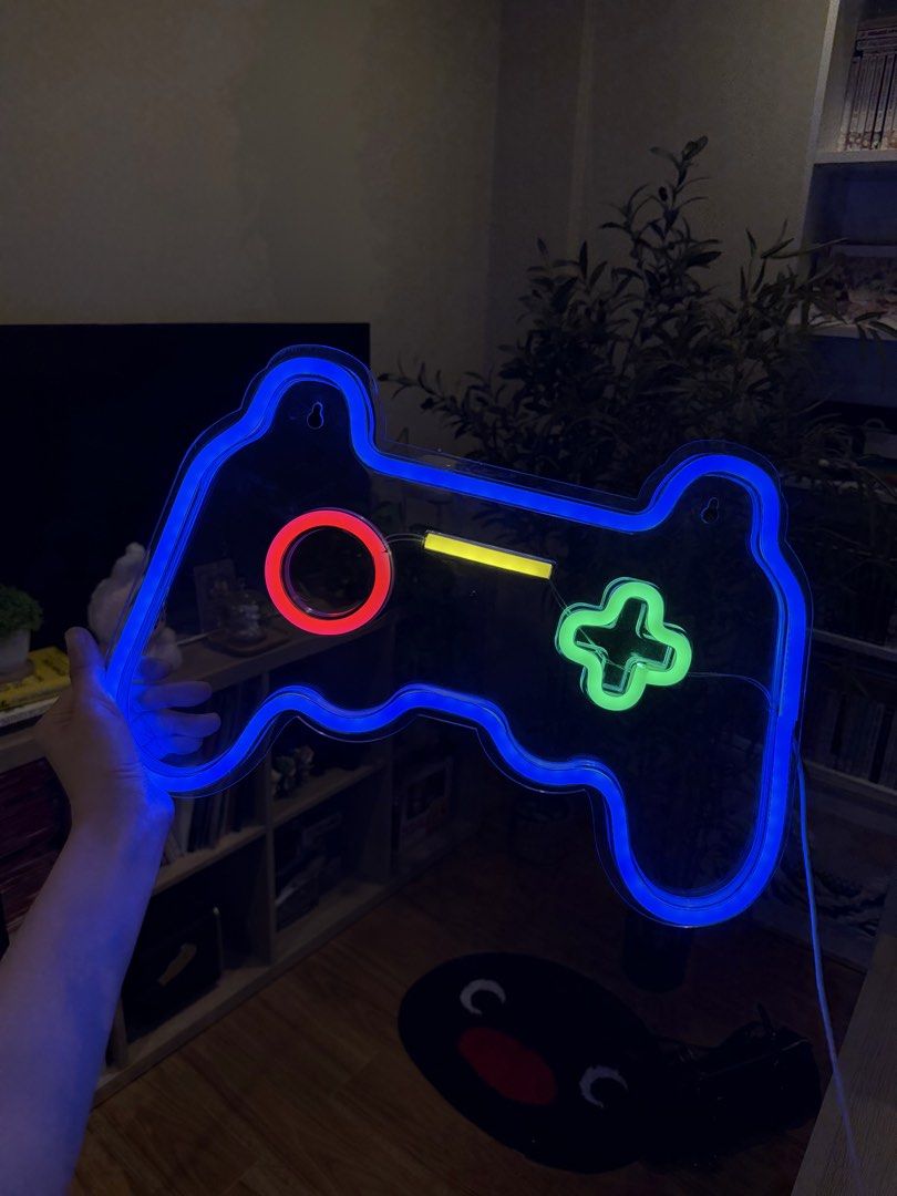 Gaming Controller LED Neon Light Sign Wall Decor (Category: Controllers) located in Quezon City. Submitted by rochichan (Listing ID 1465663388, Image 2). Description: - Design: Gamepad-shaped LED neon light with bright blue outline and multi-color accents (red, yellow, green) - Power: Convenient USB-powered cable included - Usage: Perfect for bedroom walls, gaming setups, or streaming backdrops - Condition: Brand new, powers on nicely with a vivi