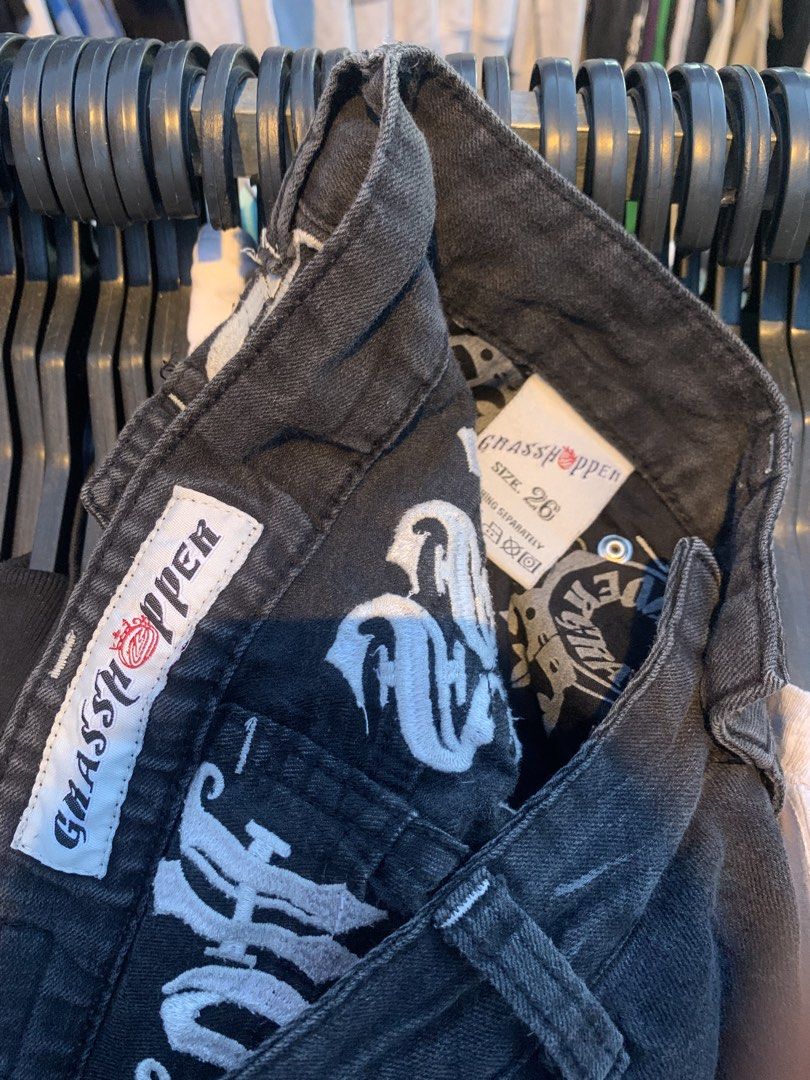 Grasshopper Black Embroidered Denim Jeans Size 26 (Category: Jeans) located in Naga. Submitted by than09070539101 (Listing ID 1465666813, Image 3). Description: - Brand/Model: Grasshopper Black Denim Jeans - Size: 26 - Design: Gothic white embroidery on back yoke and pockets - Details: Large cross patches on right leg and back pocket - Pockets: Button flap back pockets with metal hardware - Wash: Dark wash faded black denim - Branding: Leather wa