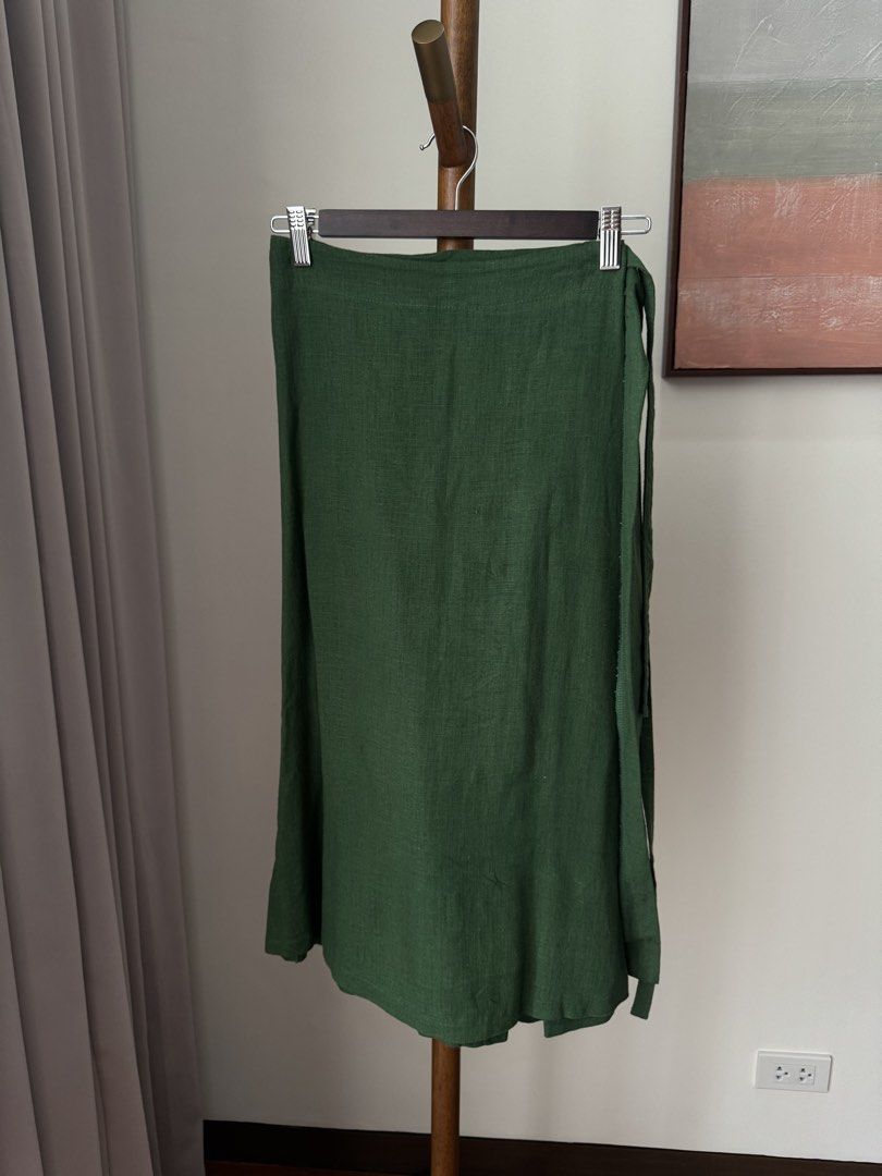 Green Wrap Skirt Linen Midi (Category: Skirts) located in Pasig City. Submitted by kutleyn (Listing ID 1465697220, Image 1). Description: - Color: Rich forest green - Style: Classic wrap midi skirt with adjustable side tie closure - Fabric: Lightweight material with a beautiful drape - Perfect for: Warm weather, casual outings, and everyday wear - Versatility: Easy to pair with basic tees or chic blouses.