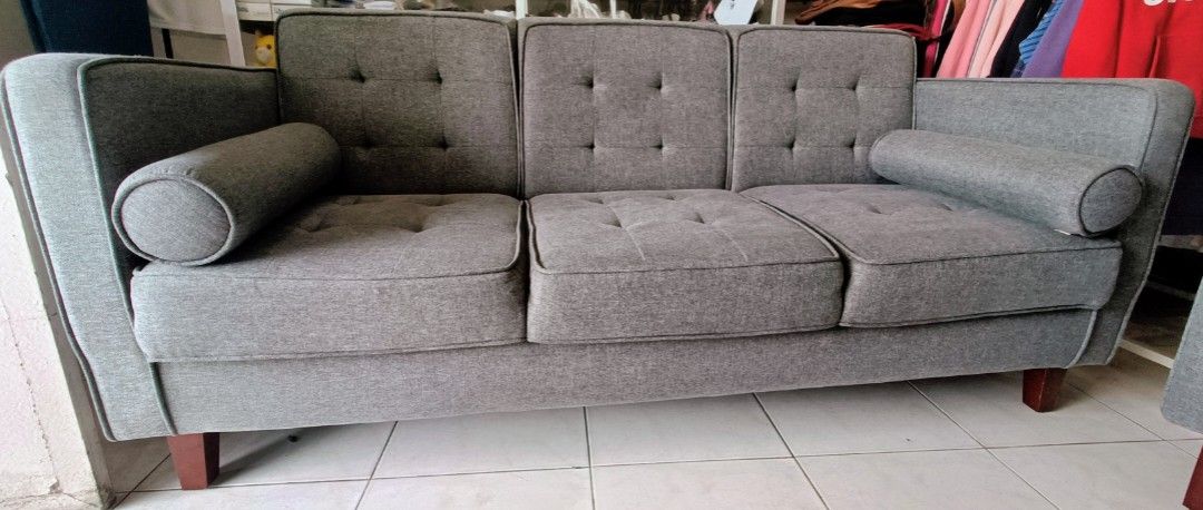Grey Fabric Sofa Mandaue Foam (Category: Sofas) located in Las Pinas. Submitted by jenny.nogu (Listing ID 1465702642, Image 1). Description: - Mandaue Foam Sofa - No lubog, no lundo, no punit - Style: Modern grey fabric sofa with a chic tufted back - Comfort: Includes two matching bolster pillows for extra support and style - Durability: Supported by sturdy wooden legs underneath - Versatility: Neutral color effortlessly matches any home interior