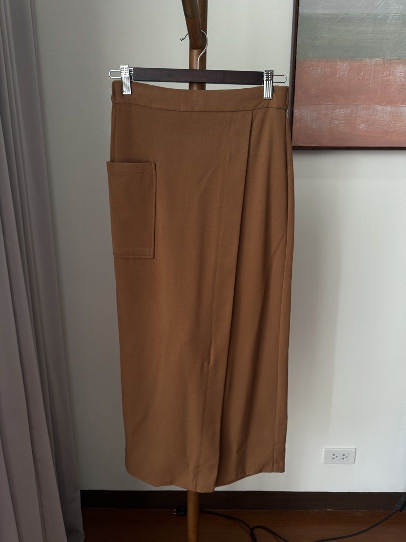 GU Brown Wrap Skirt (Category: Skirts) located in Pasig City. Submitted by kutleyn (Listing ID 1465697228, Image 1). Description: - Brand/Model: GU Wrap Skirt - Size: S - Color: Brown - Length: Midi - Design: Asymmetrical overlap front with a right-hip pocket - Material: 64% polyester, 33% rayon, 3% polyurethane (smooth with slight stretch) - Condition: Clean tag and buttons intact.