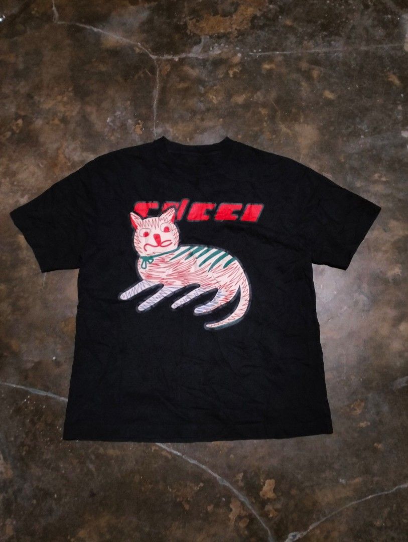GUCCI GRAFFIC SHIRT (Category: Luxury Apparel) located in Solana. Submitted by allgoodst.s (Listing ID 1465714678, Image 1). Description: GUCCI GRAFFIC SHIRT CAT DESIGN GOOD CONDITION MEDIUM TO large 9/10 CR MISSING NECK TAG, INTACK WASH TAGS hairline crack.