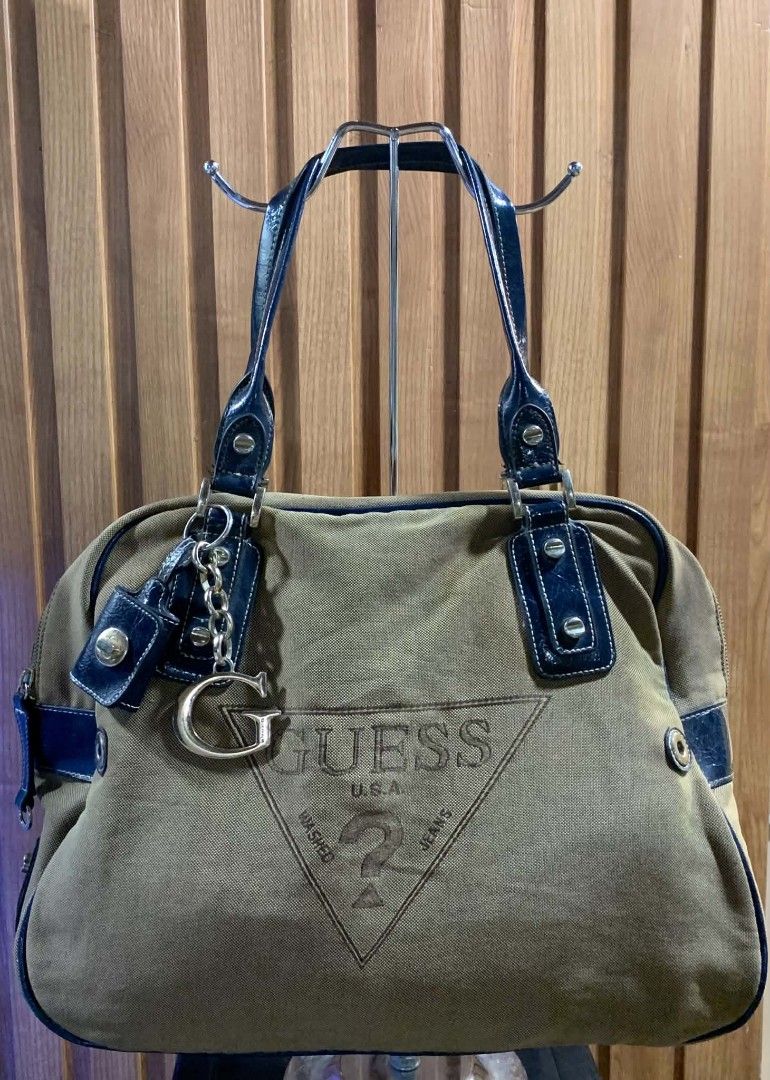 Guess Khaki and Blue Canvas Handbag (Category: Shoulder Bags) located in Manila. Submitted by kylie_jenner. (Listing ID 1465660609, Image 1). Description: - Brand: Guess - Material: Khaki canvas with blue patent leather trim - Design: Large Guess USA logo on front, silver-tone 'G' charm and padlock pendant - Handles: Double shoulder handles with metallic rivet details - Closure: Zip top closure - Condition: Clean interior and bottom base - Usage: