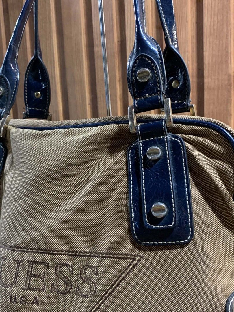 Guess Khaki and Blue Canvas Handbag (Category: Shoulder Bags) located in Manila. Submitted by kylie_jenner. (Listing ID 1465660609, Image 2). Description: - Brand: Guess - Material: Khaki canvas with blue patent leather trim - Design: Large Guess USA logo on front, silver-tone 'G' charm and padlock pendant - Handles: Double shoulder handles with metallic rivet details - Closure: Zip top closure - Condition: Clean interior and bottom base - Usage: