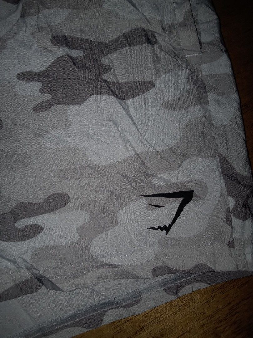 Gymshark Grey Camo Shorts Medium (Category: Shorts) located in Dumaguete. Submitted by alayon.thrifter (Listing ID 1465677761, Image 3). Description: - Brand: Gymshark - Style: Grey camo shorts - Size: Medium (Made in Cambodia) - 30 to 34 waistline - 15 length - Fit: Elastic waistband with adjustable drawstring - Details: Gymshark logo near bottom hem, wash care label attached - Condition: Great for workouts or lounging.