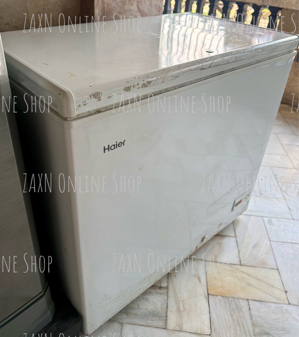 Haier White Chest Freezer (Category: Refrigerators and Freezers) located in Santa Cruz. Submitted by za2011za (Listing ID 1465581912, Image 3). Description: - Brand: Haier chest freezer - Color: White - Features: Top-opening lid with built-in lock, interior wire storage basket, and front control panel with power indicator - Condition: Cools well; exterior shows a bit scratches, scuffs, and paint wear around the edges near the lid seal due to stor