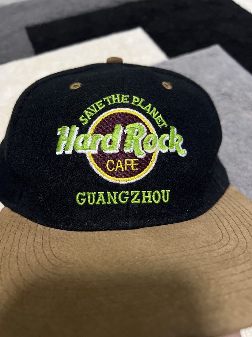 Hard Rock Cafe Guangzhou Save The Planet Cap (Category: Caps & Hats) located in Calasiao. Submitted by pb.supply_v2 (Listing ID 1465752640, Image 2). Description: - Brand: Hard Rock Cafe Guangzhou - Design: Black body with a contrasting brown brim - Embroidery: 'Save The Planet' and 'Guangzhou' on the front; 'Love All Serve All' in yellow on the back - Fit: Adjustable plastic snap closure - Condition: Excellent, ready to wear.