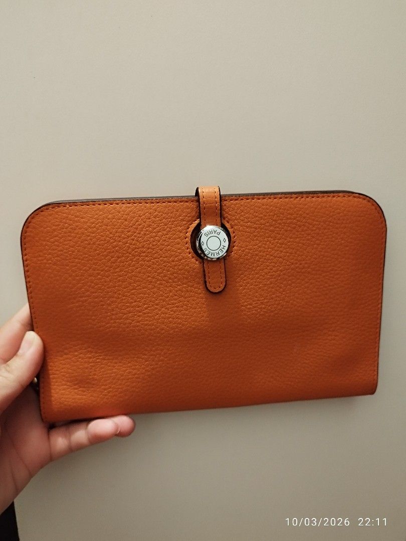 Hermès Orange Leather Wallet (Category: Wallets & Card holders) located in Cebu City. Submitted by jlorana11395954 (Listing ID 1465717888, Image 1). Description: - Brand: Hermès - Color: Iconic Hermès Orange - Material: Premium leather with clean stitching - Closure: Distinctive front flap clasp - Interior: Zippered compartment and multiple card slots - Bonus: Includes a matching removable zipped pouch insert - Design: Compact size, easy to slip 