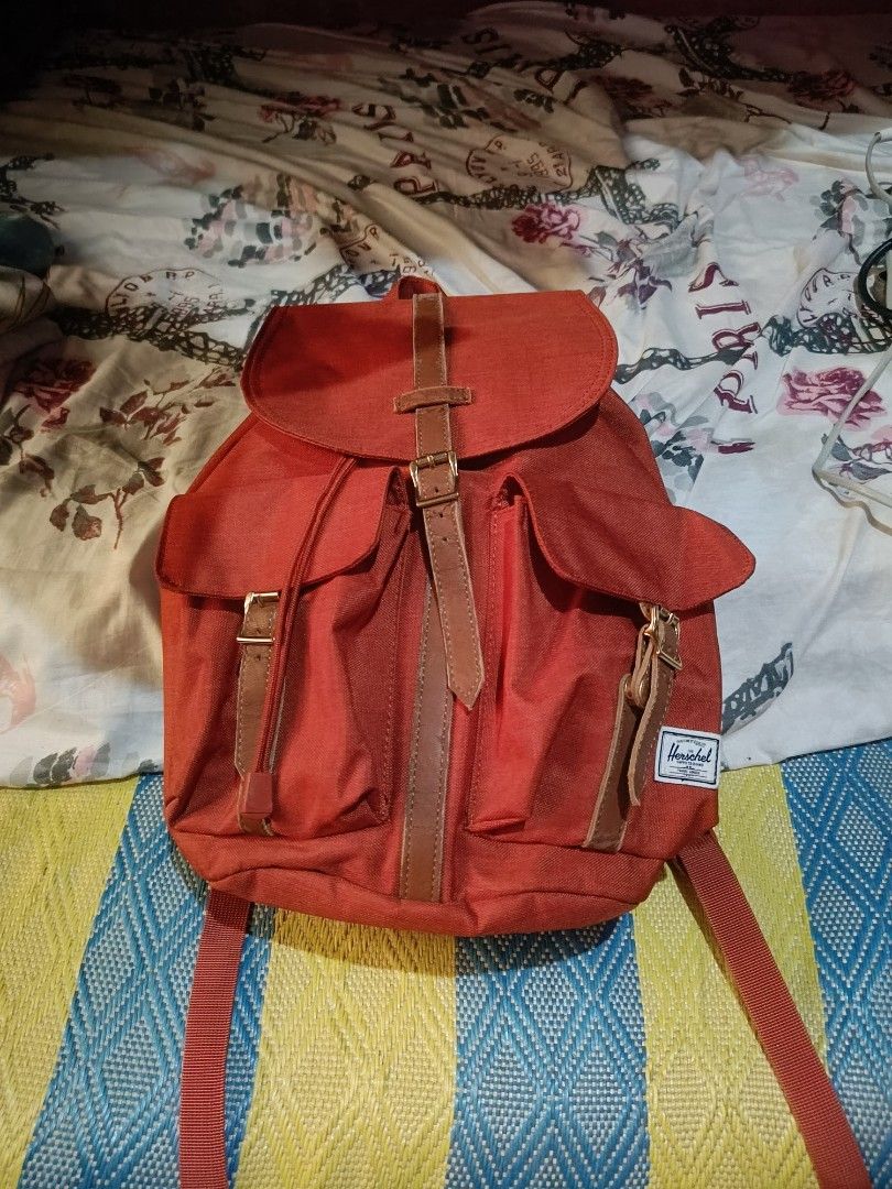 Herschel Dawson (Category: Backpacks) located in Urdaneta. Submitted by tetsudoubletaps (Listing ID 1465666419, Image 1). Description: + SF Goods na goods pa yung tela as in, natambak lang kaya mejo may cracks sa leather pero minimal. - Brand: Herschel - Color: Vibrant red with contrast brown faux leather straps and sturdy metal hardware - Storage: Main compartment with secure drawstring cinch and flap top, two front buckle pockets, and an interi
