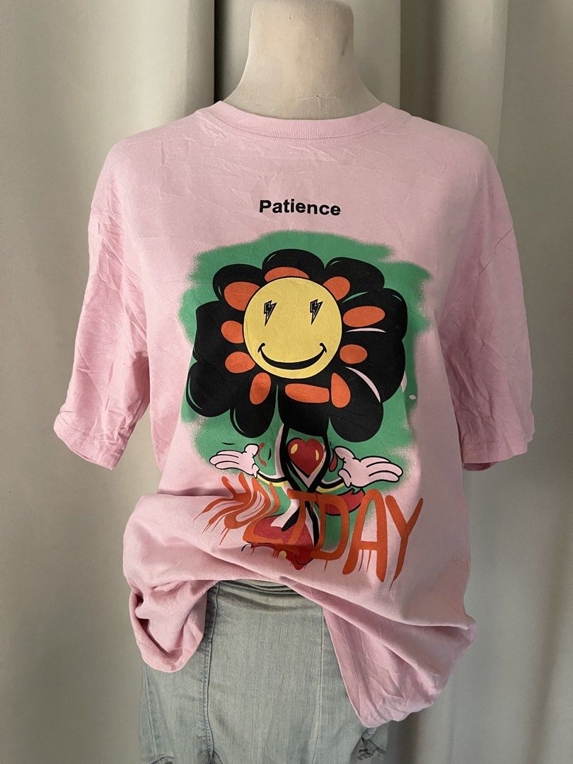 hq cotton pink tee (Category: Shirts) located in Cainta. Submitted by zlove111 (Listing ID 1465758044, Image 2). Description: - Color: Pink - Style: Casual streetwear, relaxed fit - Design: Large colorful flower graphic with lightning bolt eyes and 'Patience/HOLIDAY' text - Neckline: Crew neck - Condition: Excellent, clean with no stains or damage.