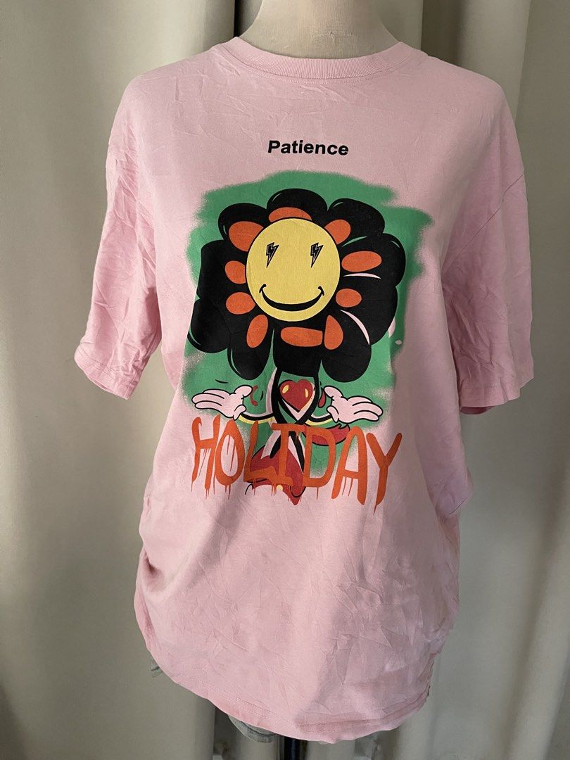 hq cotton pink tee (Category: Shirts) located in Cainta. Submitted by zlove111 (Listing ID 1465758044, Image 1). Description: - Color: Pink - Style: Casual streetwear, relaxed fit - Design: Large colorful flower graphic with lightning bolt eyes and 'Patience/HOLIDAY' text - Neckline: Crew neck - Condition: Excellent, clean with no stains or damage.