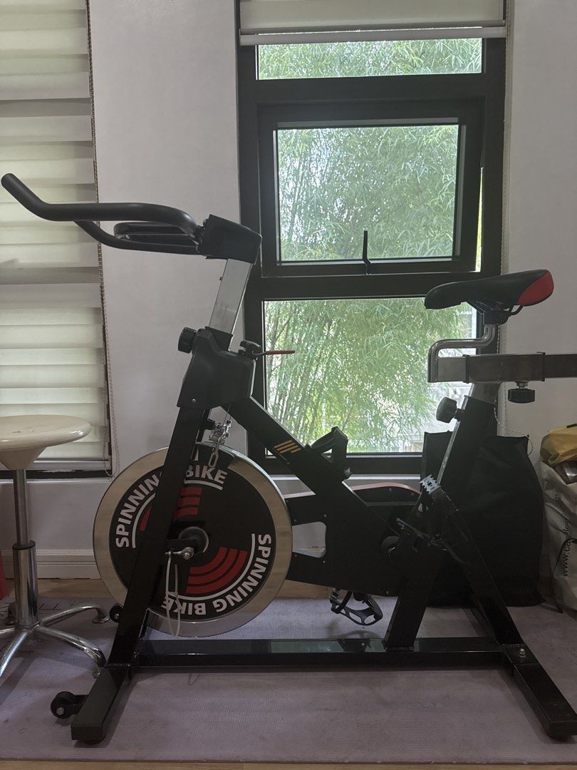 Indoor Spinning Bike (Category: Cardio & Fitness Machines) located in Quezon City. Submitted by jbeans814 (Listing ID 1465586471, Image 1). Description: - Indoor stationary spinning bike perfect for home workouts - Heavy metal flywheel with striking red and white branding - Sturdy black steel frame with a compact footprint for small spaces - Adjustable handlebars and cushioned seat for a comfortable ride - Multi-grip handle setup with an integrat