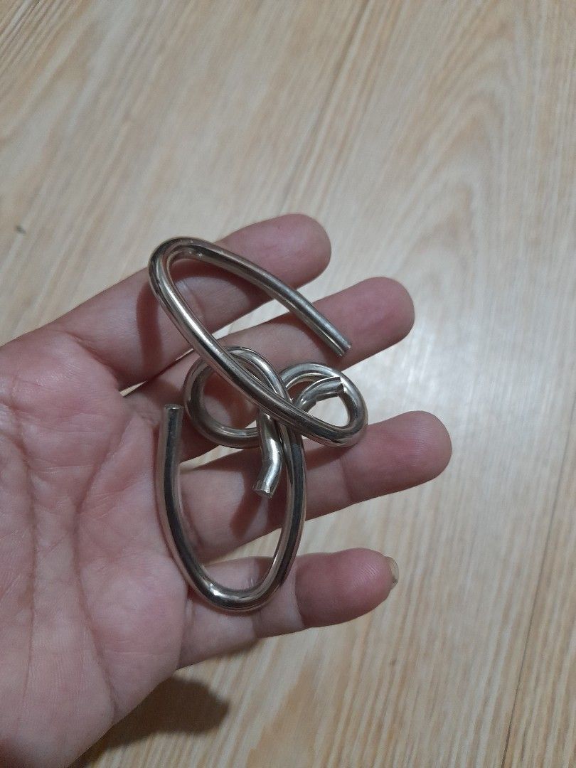 Interlocking metal wire puzzle brain teaser (Category: Board Games & Puzzles) located in Bocaue. Submitted by marajapansurplus (Listing ID 1465699970, Image 1). Description: - Compact metal wire puzzle fits in your palm - Durable silver-toned solid construction - Twist and maneuver pieces to separate them - Perfect brain teaser for travel or downtime - Standard cast puzzle size.