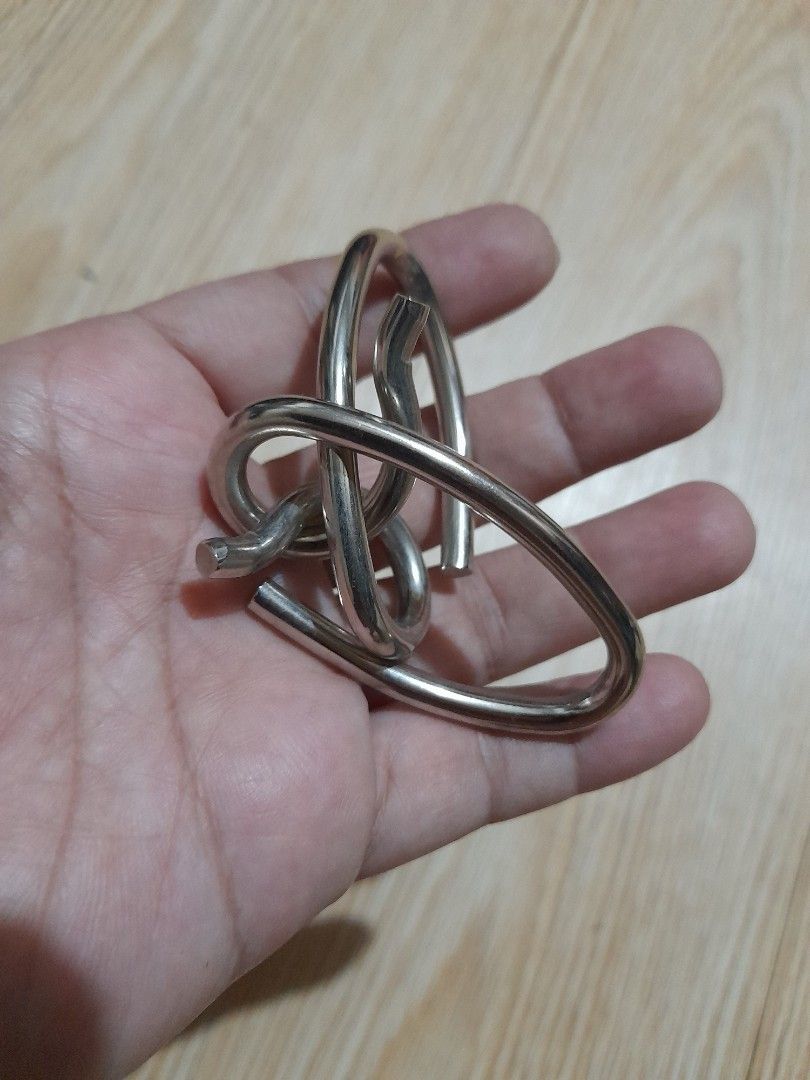 Interlocking metal wire puzzle brain teaser (Category: Board Games & Puzzles) located in Bocaue. Submitted by marajapansurplus (Listing ID 1465699970, Image 3). Description: - Compact metal wire puzzle fits in your palm - Durable silver-toned solid construction - Twist and maneuver pieces to separate them - Perfect brain teaser for travel or downtime - Standard cast puzzle size.