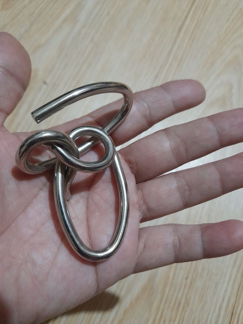 Interlocking metal wire puzzle brain teaser (Category: Board Games & Puzzles) located in Bocaue. Submitted by marajapansurplus (Listing ID 1465699970, Image 2). Description: - Compact metal wire puzzle fits in your palm - Durable silver-toned solid construction - Twist and maneuver pieces to separate them - Perfect brain teaser for travel or downtime - Standard cast puzzle size.