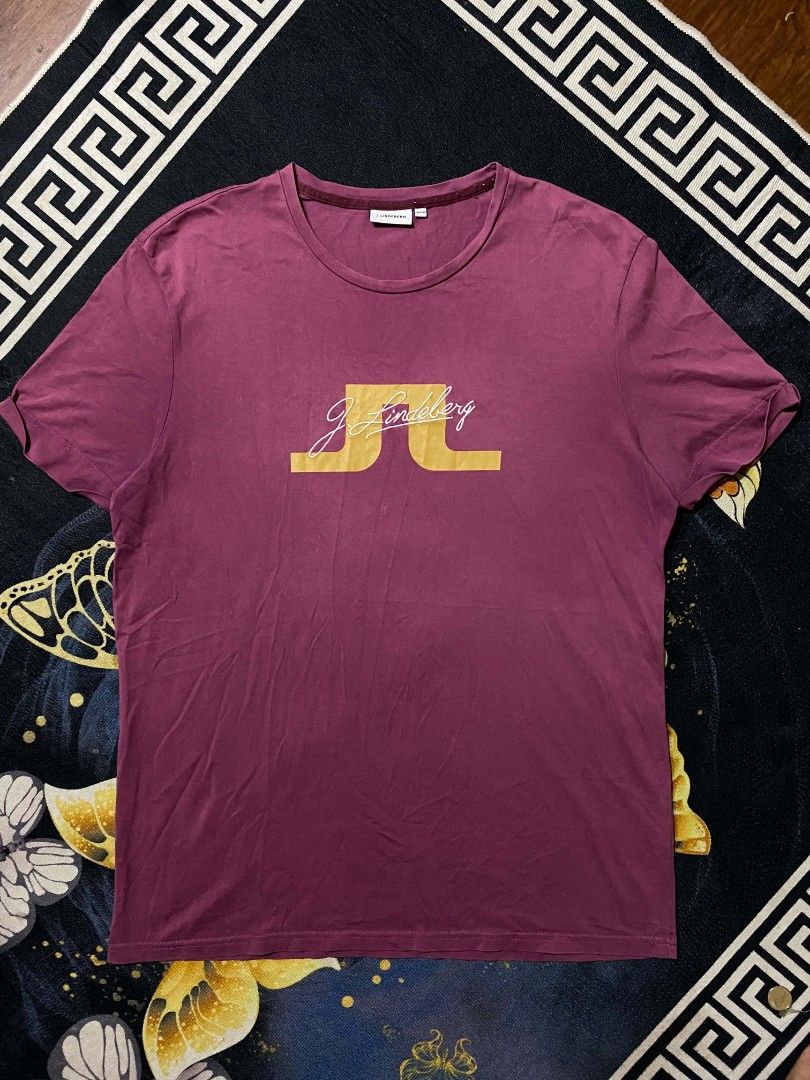 j.lindeberg shirt (Category: Tshirts & Polo Shirts ) located in Manila. Submitted by thrift_sta.20 (Listing ID 1465674841, Image 1). Description: - Brand: J.Lindeberg - Color: Dark Purple - Size: 185/104A - Material: 100% soft cotton for all-day comfort - Design: Large gold logo print with white embroidered script on the chest - Details: Classic ribbed crew neckline - Condition: Clean inside and out, great for casual wear.