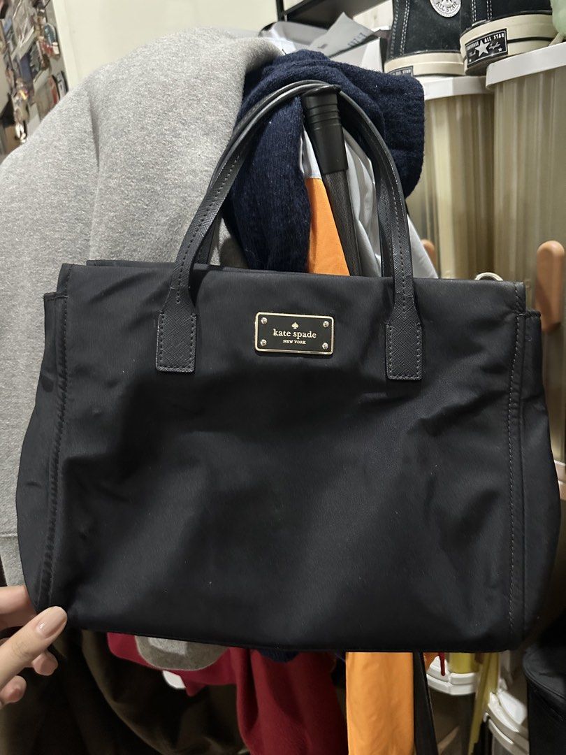 Kate Spade Black Nylon Tote Handbag (Category: Tote Bags) located in Quezon City. Submitted by cassie.u (Listing ID 1465642946, Image 1). Description: - Brand: Kate Spade New York - Material: Durable black nylon with textured leather double handles - Hardware: Elegant gold-tone hardware and signature front plaque - Interior: Fully lined with logo jacquard fabric, featuring a center zip compartment and side slip pockets - Condition: Lightly used N