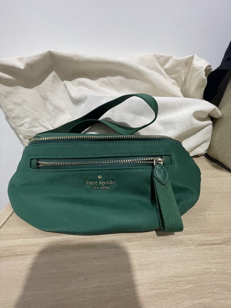 Kate Spade Green Nylon Belt Bag (Category: Cross-body Bags) located in Cordova. Submitted by fiercedragon.47e450 (Listing ID 1465710091, Image 3). Description: - Brand: Kate Spade - Color: Deep Green - Material: Durable nylon with gold-tone hardware - Compartments: Main zip compartment + exterior front zip pocket - Strap: Adjustable with metal buckle closure - Details: Metallic logo lettering stamped on the front - Condition: Brand new / Excellen