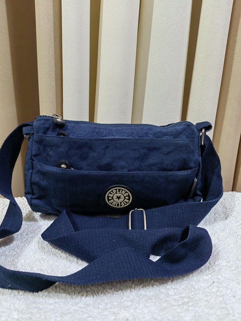 Kipling blue crossbody bag (Category: Cross-body Bags) located in Makati City. Submitted by prelovedtreatedwithlove (Listing ID 1465622471, Image 2). Description: - Kipling blue crossbody bag - Durable and lightweight nylon material - Multiple exterior zipper pockets for easy organization - Comfortable adjustable blue shoulder strap - Clean interior lined with patterned fabric plus an extra zip pocket - issue: hardware rust. Last pic for referenc