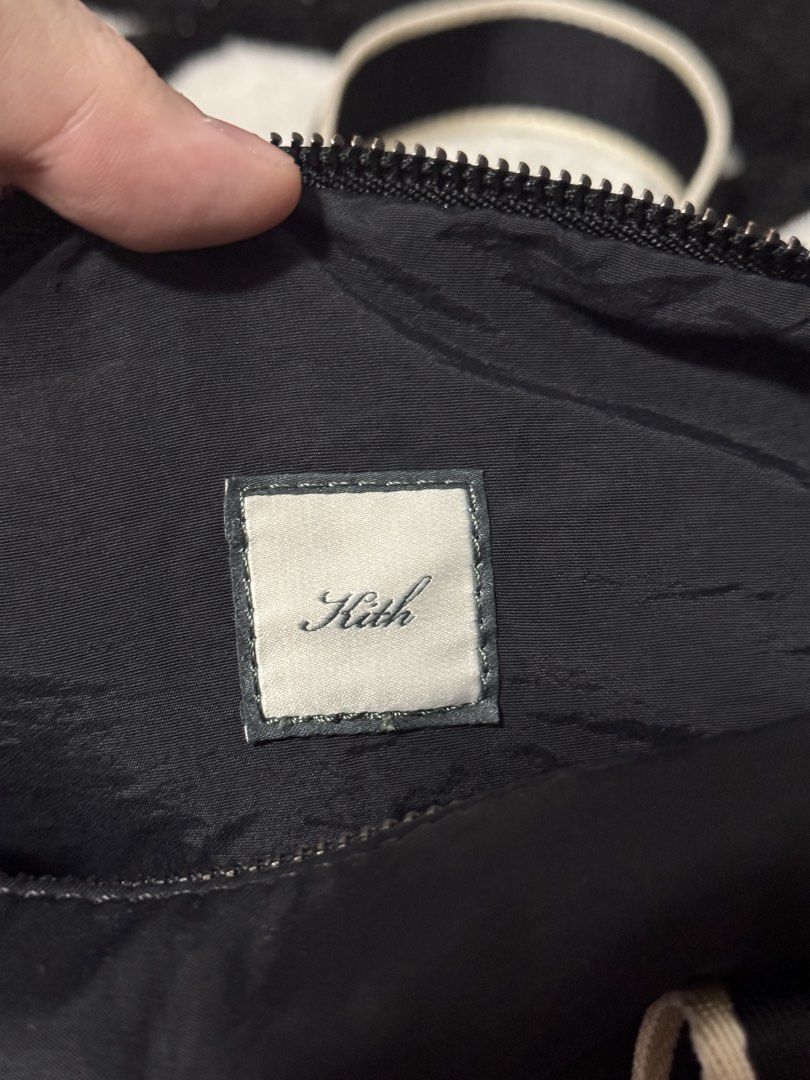 Kith Mini Duffle Bag (Category: Cross-body Bags) located in Makati City. Submitted by yougotmarc13 (Listing ID 1465623541, Image 3). Description: Kith black mini duffle bag with beige piping and branded straps. Script logo embroidery on handles and shoulder strap. Zipper closure with custom Kith hardware. Interior zip pocket and slip pocket included. Comes with original cream dust bag featuring the boxed Kith logo..