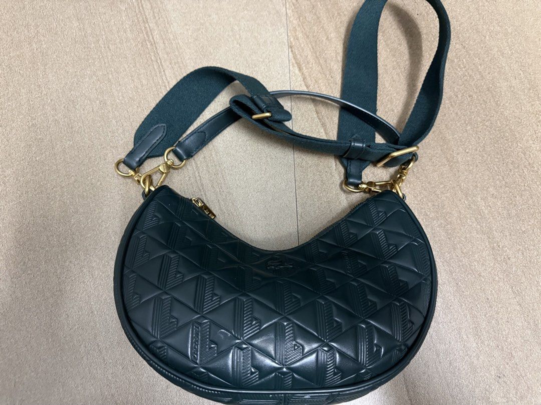 Lacoste Black Monogram Crescent Crossbody Bag (Category: Cross-body Bags) located in Pasig City. Submitted by cvj25 (Listing ID 1465686070, Image 1). Description: - Brand: Lacoste Original Price: 15,000 - Style: Crescent crossbody bag in classic black - Design: Embossed geometric monogram pattern with gold-toned hardware - Strap: Adjustable fabric strap for comfortable wear - Interior: Cream-coloured lining with a branded leather inner pocket - C
