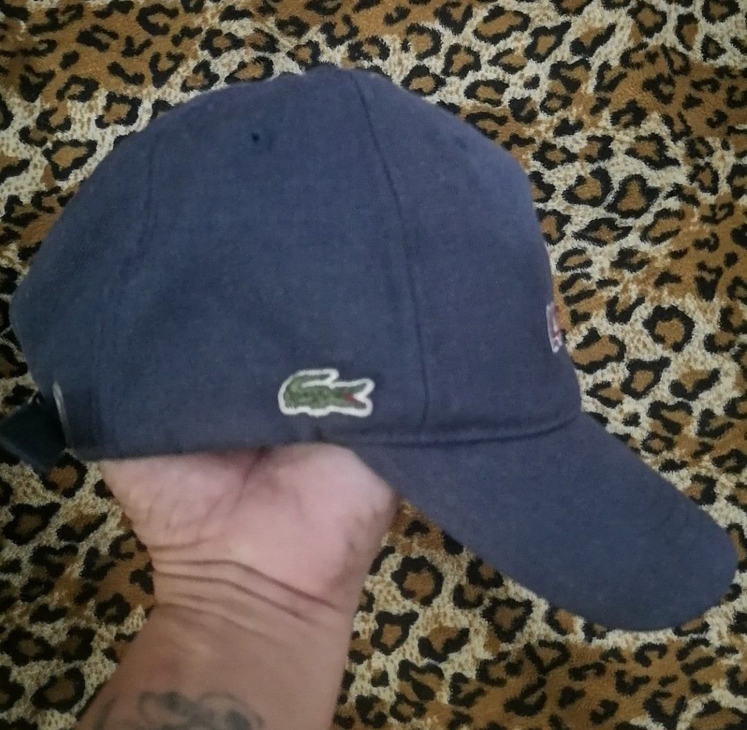 Lacoste navy blue embroidered baseball cap (Category: Caps & Hats) located in Cebu City. Submitted by roadthrift (Listing ID 1465702473, Image 2). Description: - Brand: Lacoste - Color: Navy blue with white embroidered lettering and green crocodile logo - Hardware: Adjustable strap with Lacoste-engraved metal buckle - Authenticity: Interior material and product code tags intact.