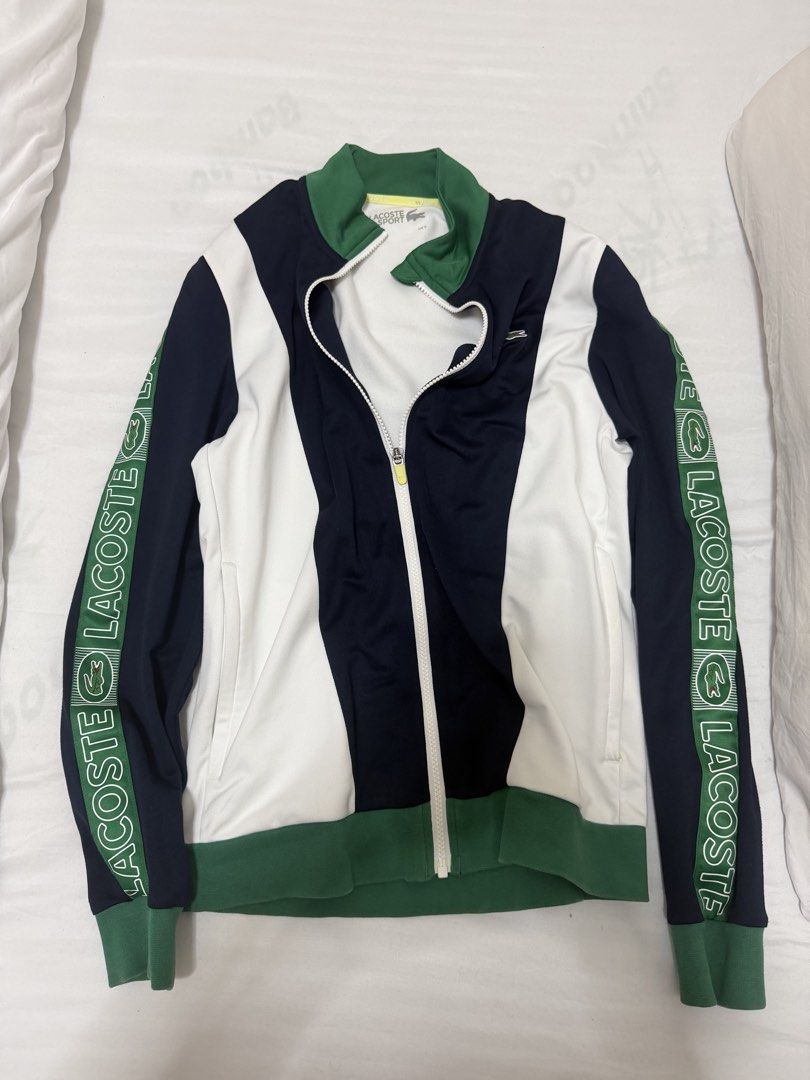 Lacoste Sport Zip Jacket (Category: Coats, Jackets and Outerwear) located in Santa Rosa. Submitted by decluttering_. (Listing ID 1465699886, Image 1). Description: AUTHENTIC - Brand: Lacoste Sport - Design: Navy, white, and green colorblock with bold sleeve lettering tape - Features: Full zip front, stand collar, ribbed green cuffs and hem - Size: US Small - Condition: Clean overall, great for gym or casual wear.