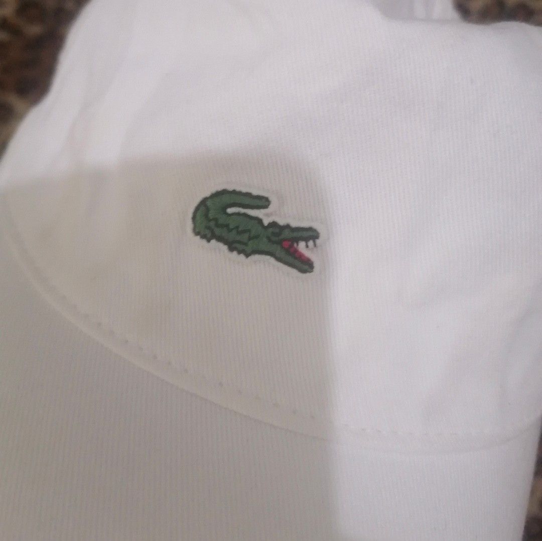 Lacoste White Baseball Cap (Category: Caps & Hats) located in Cebu City. Submitted by roadthrift (Listing ID 1465702576, Image 2). Description: - Brand: Lacoste - Color: Clean White - Material: 100% Cotton - Logo: Classic embroidered green crocodile on front - Closure: Adjustable metal strap with engraved brand name - Size: One size fits all (Unisex) - Condition: Excellent, minimal signs of wear - Origin: Made in China.